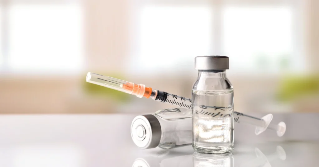 Vials of vitamin injections and a syringe on a reflective surface in Grand Blanc, MI